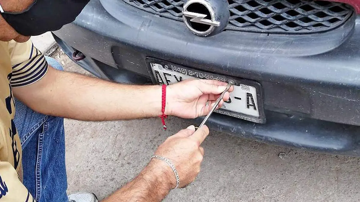 hombre ajusta placa a un vehiculo